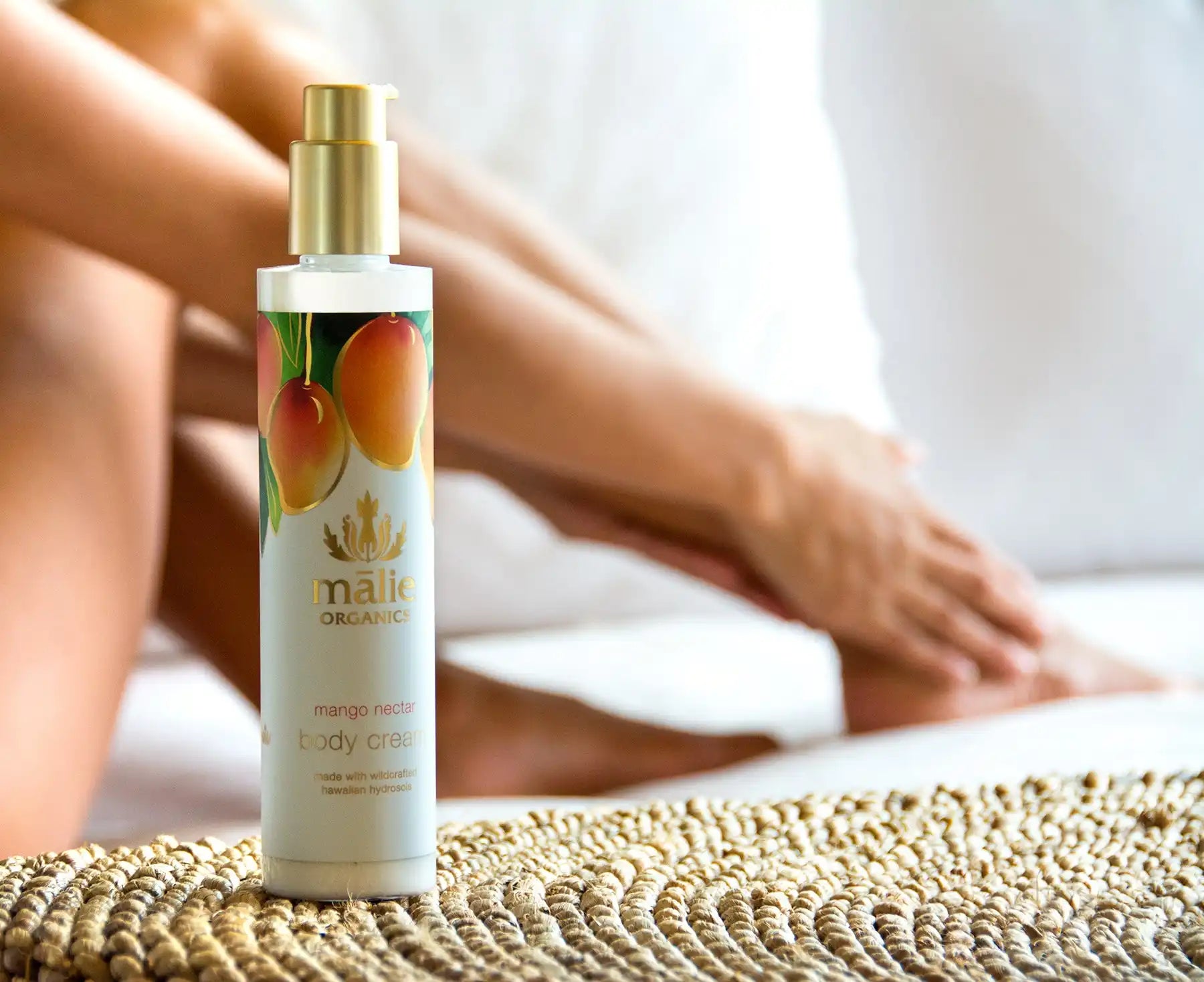 A body lotion bottle with mango fruit graphics on white packaging.