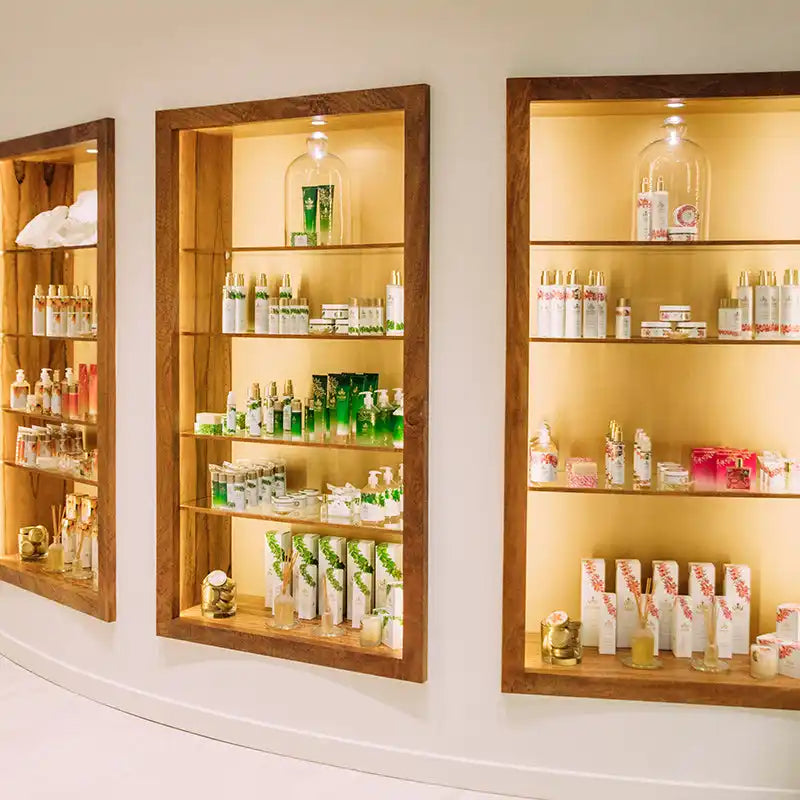 Built-in wooden display shelves with illuminated glass bottles and beauty products.