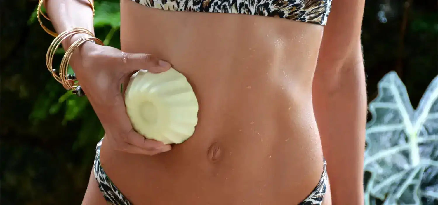 Half of a fresh, pale green honeydew melon being held against a torso.