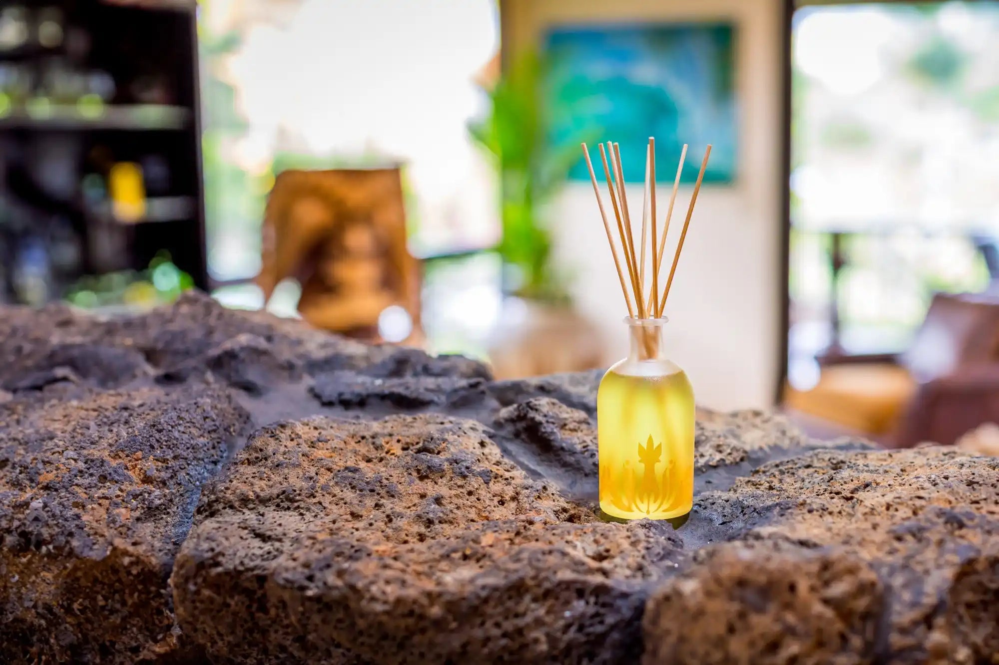 Reed diffuser with yellow-tinted oil in a glass bottle.