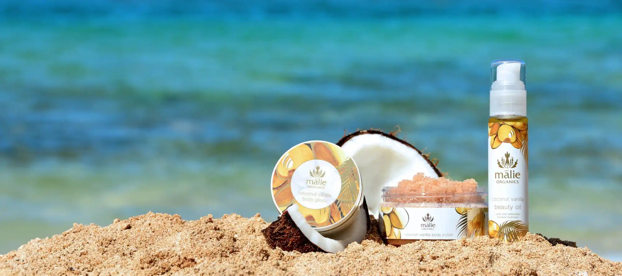 Skincare or beauty products arranged on beach sand.