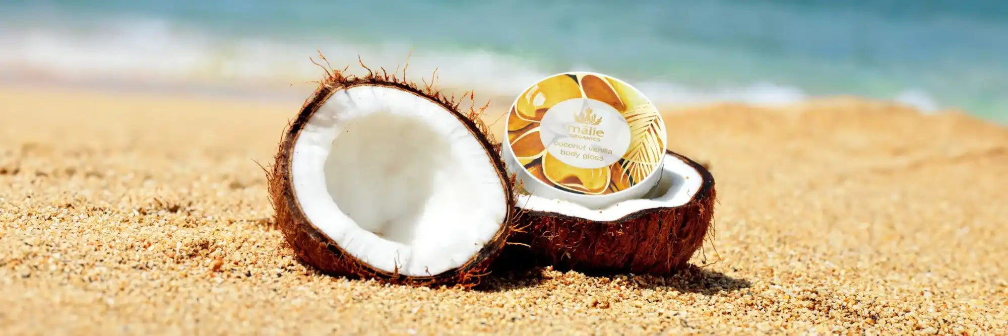 Split coconut with white flesh on sandy beach.