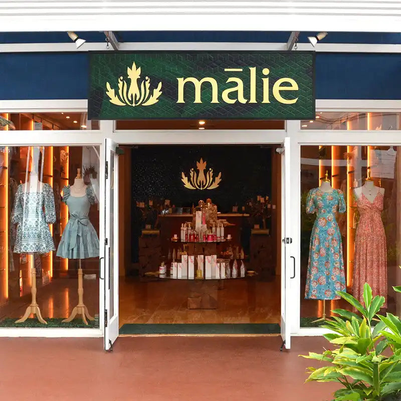 Storefront of a Malie boutique with floral dresses displayed in the windows.