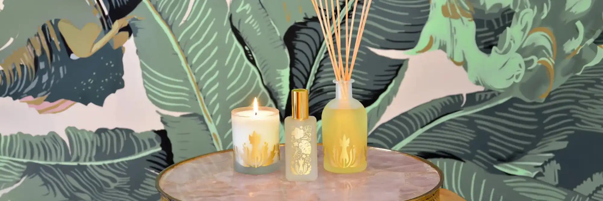 Three glass jars with reed diffusers on a round table.