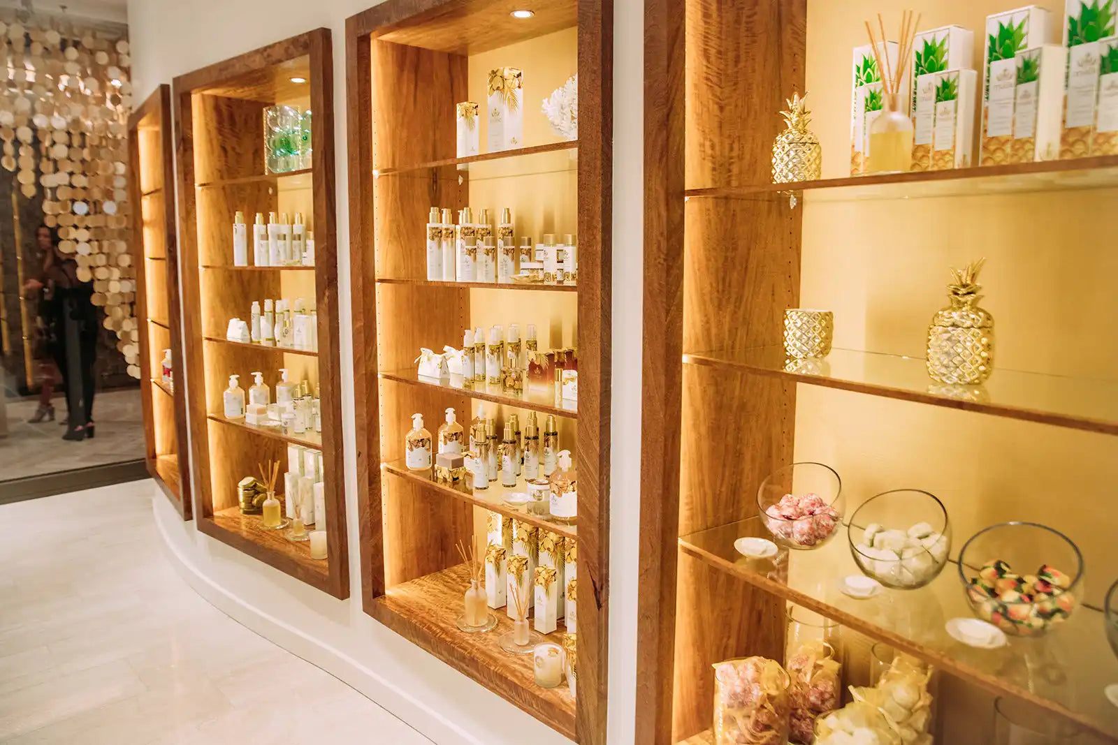 Wooden display shelves with illuminated compartments showcasing bottles and decorative items.